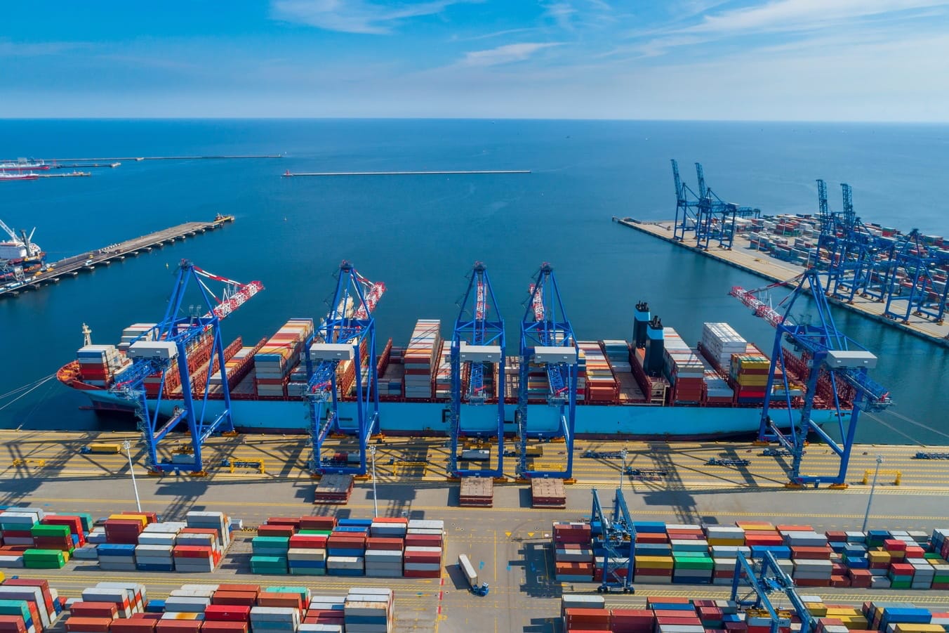 Hafenbecken mit Containerschiff bei der Beladung – Symbol für weltweiten Seetransport.