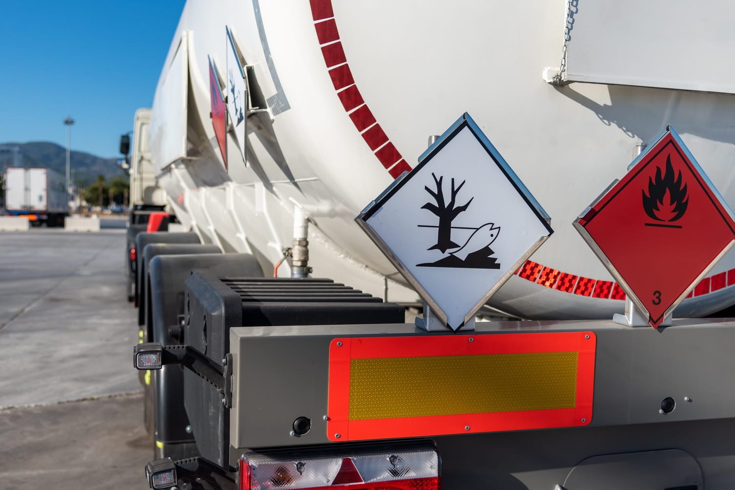 Nahaufnahme von ADR-Gefahrgutkennzeichnungen (umweltgefährdend und entzündbar) am Heck eines weißen Tank-LKW.