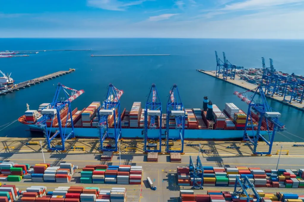 Großer Containerhafen mit Frachtschiff und Verladekränen für weltweite Seefracht.